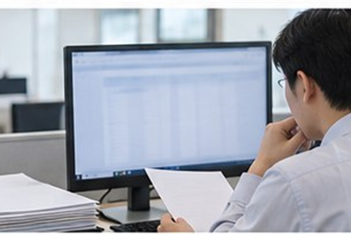 신주발행무효소송 관련 기업 행정 담당자가 컴퓨터와 빈 문서로 등기 일정을 점검하는 사무실